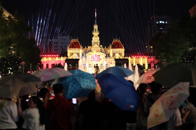 People brave the rain to watch the 3D mapping performance in front of the Ho Chi Minh City People's Committee headquarters. Photo: Thai Bao