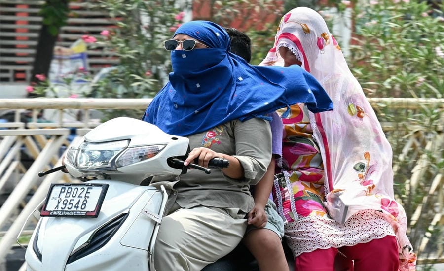 Người dân Ấn Độ che chắn để tránh nắng khi đi ra ngoài đường ngày 29.6. Ảnh: AFP
