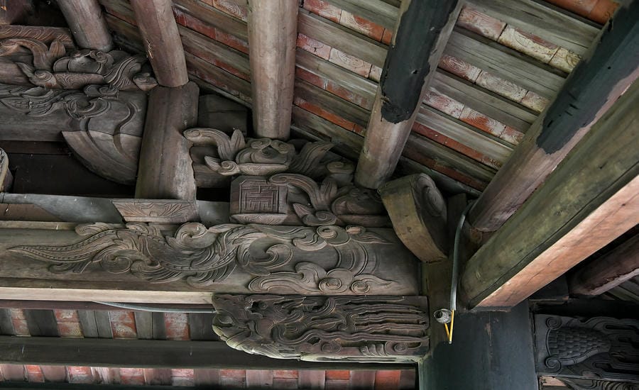 Những mảng chạm khắc gỗ tinh xảo trên hệ vì kèo (bộ khung kết cấu bằng gỗ đỡ toàn bộ mái của chùa Hang (Kim Sơn Tự) phản ánh nghệ thuật kiến trúc truyền thống Việt Nam, nơi mỗi đường nét đều mang ý nghĩa biểu tượng về sự hài hòa giữa con người và thiên nhiên.
