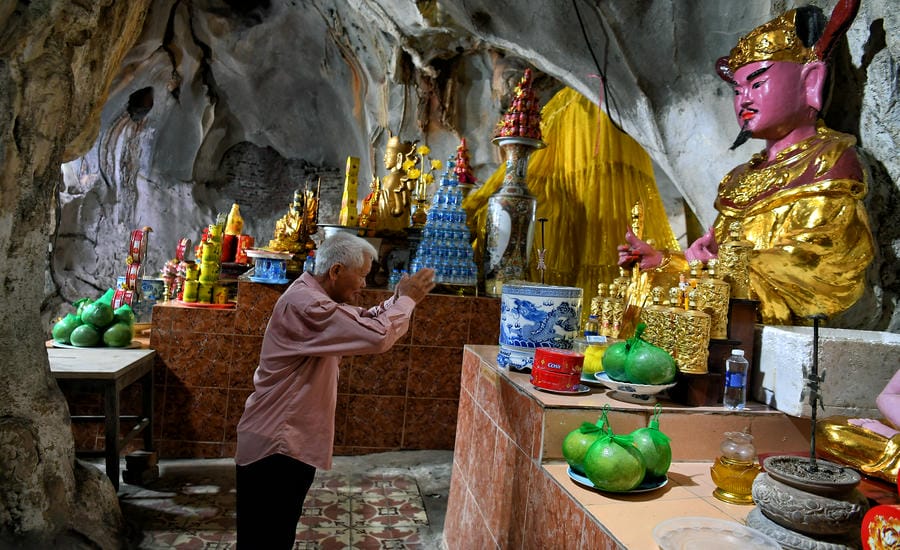 Một Phật tử thành kính dâng hương, cầu nguyện trong chính điện chùa Hang, nơi tín ngưỡng và thiên nhiên cùng tồn tại suốt nhiều thế kỷ.