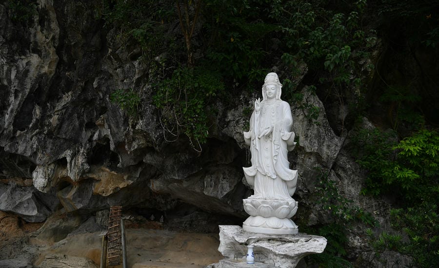 Tượng Quán Thế Âm Bồ Tát bên cửa động đá, nơi thiên nhiên và không gian Phật giáo hòa quyện, tạo nên nét riêng của chùa Hang.