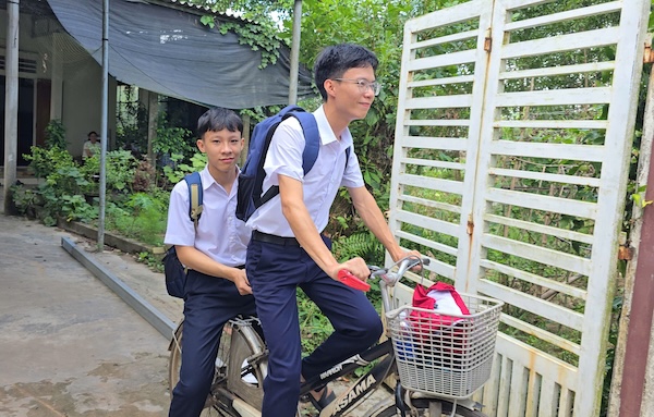 Vũ (lái xe) và Khải trên chiếc xe đạp thường sử dụng để đến trường. Ảnh: Hưng Thơ