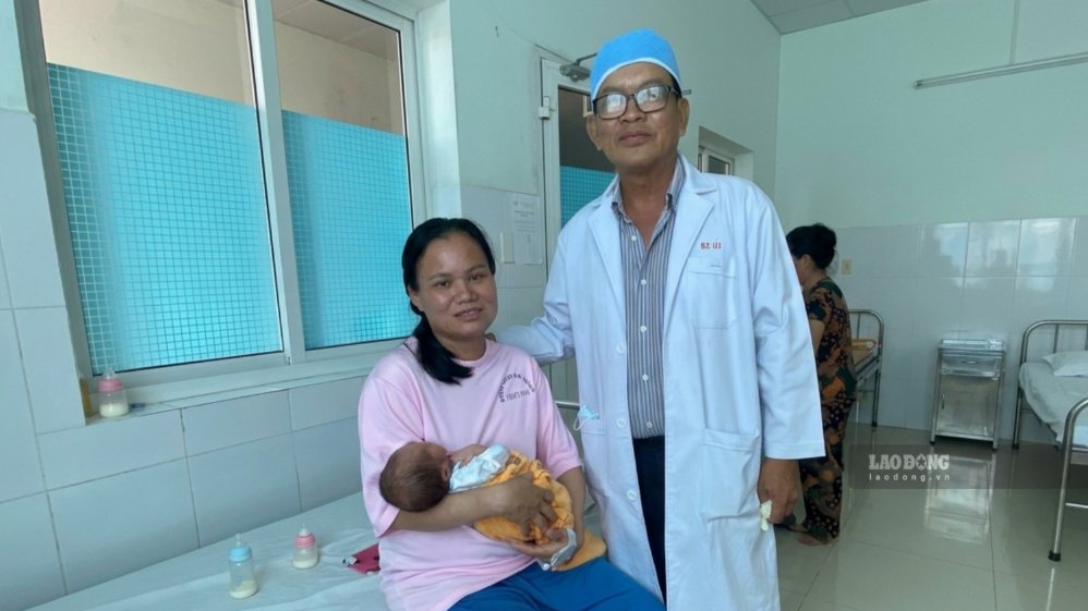 BS.CKI Do Van Ut takes photos with the pregnant woman and the baby after successful surgery to treat HELLP syndrome at Vinh Long General Hospital. Photo: Hoang Loc