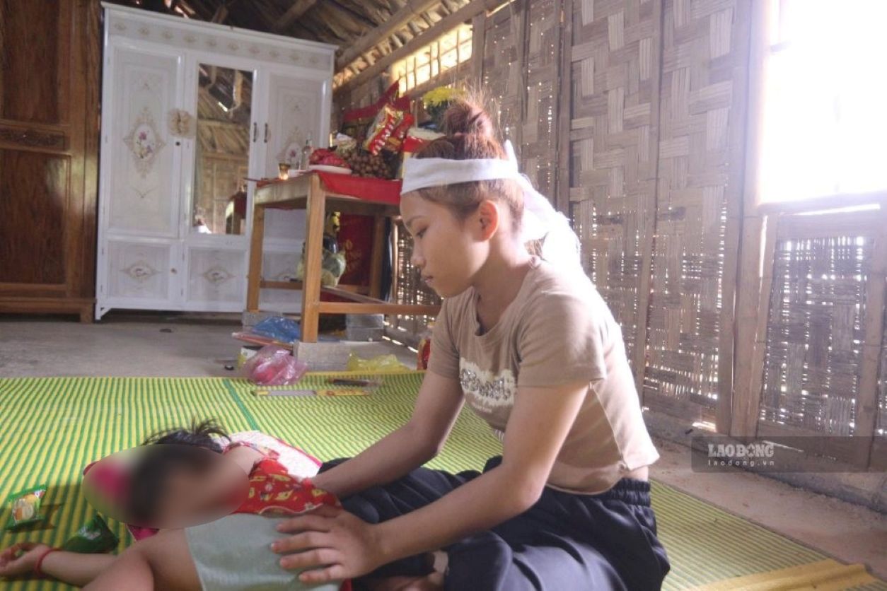 Chị Lệ đau buồn bên con thơ từ nay không còn được bố ôm ấp, yêu thương. Ảnh: Minh Hoàng