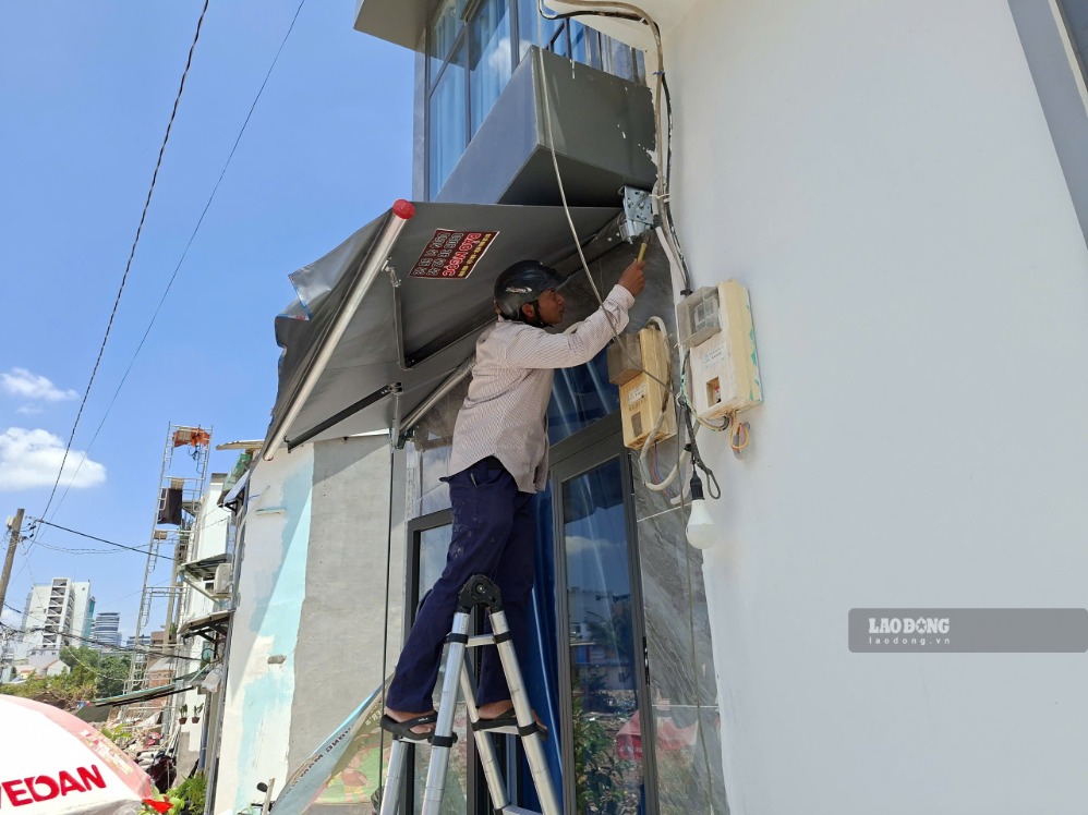 Bà Hiền thuê người gắn mái che nắng cho căn nhà.  Ảnh: Minh Quân