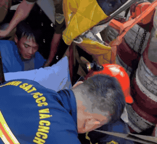 Police break down the cabin door, rescue trapped driver after container overturning. Photo: Huu Long