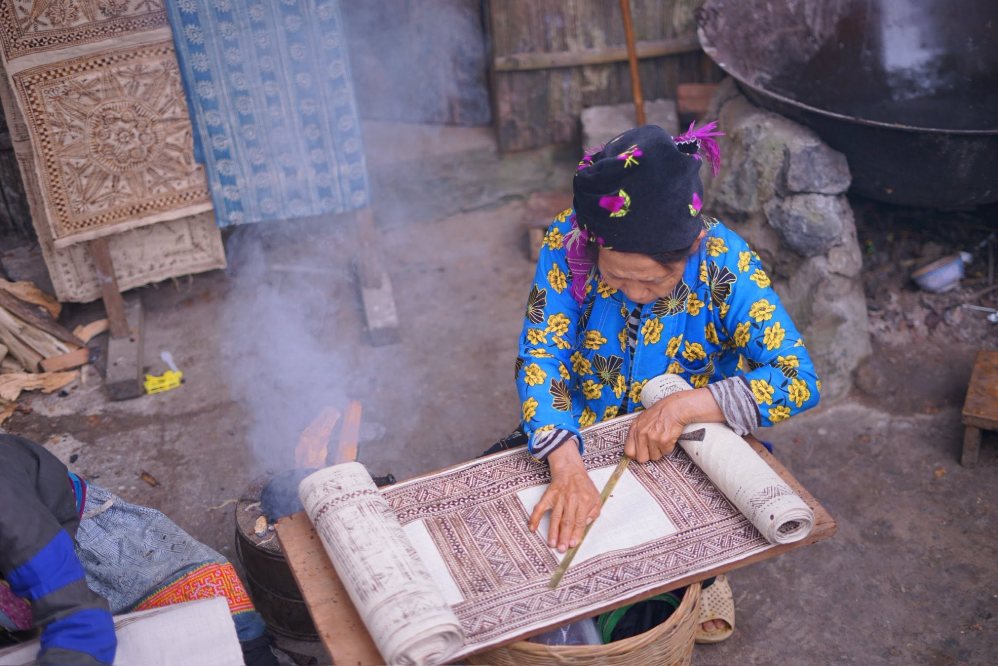 Người phụ nữ tỉ mỉ vẽ từng họa tiết lên vải lanh.