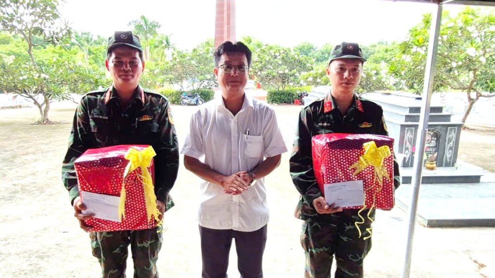 Chairman of Tri Ton Commune People's Committee - Tran Van Cuong presents gifts to officials and employees who are performing the task of taking biological samples for DNA testing of martyrs' remains at Tri Ton Martyrs' Cemetery. Photo: Phuong Vu
