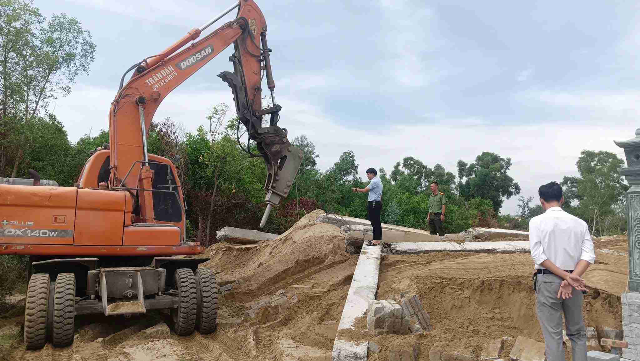Người dân sử dụng máy móc tháo dỡ lăng mộ kiên cố, trả lại đất cho địa phương. Ảnh: Duy Chương