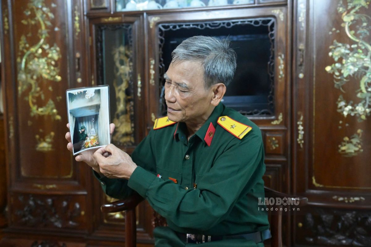 Mr. Huyen looks at a photo taken at the grave of martyr Bui Nang Dac. Photo: Luong Ha