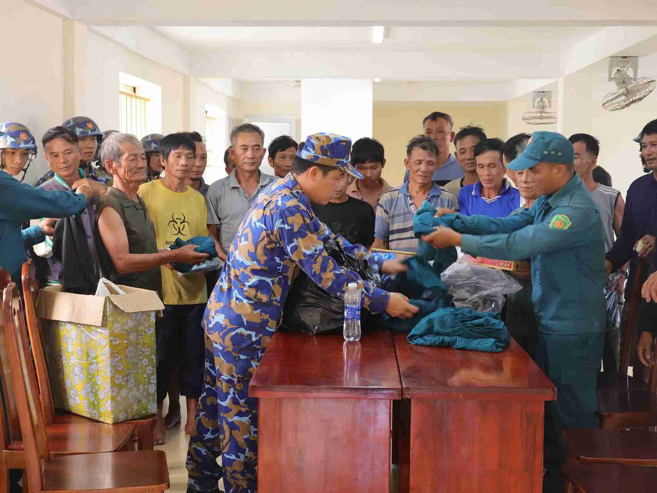 Cán bộ, chiến sĩ, Tiểu đội dân quân và các lực lượng trên đảo cấp phát quần áo, nhu yếu phẩm cho ngư dân. Ảnh: Vùng 4 Hải quân