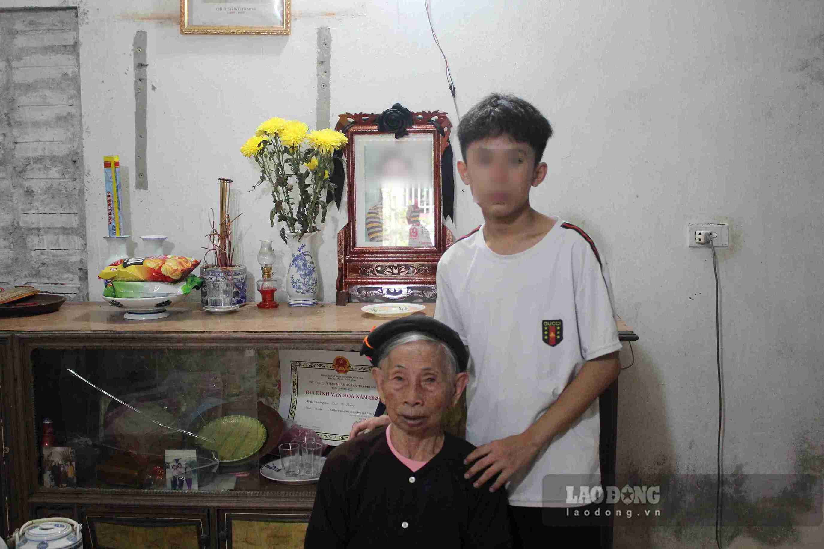 Đạt cùng bà ngoại ngồi trước di ảnh người mẹ đã khuất. Ảnh: Mai Hương