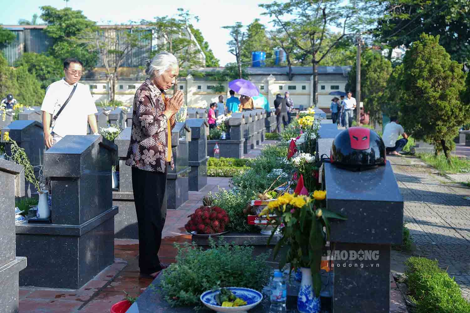 Ms. Nguyen Thi Tuat next to her brother's grave as a martyr. Photo: Song Huu