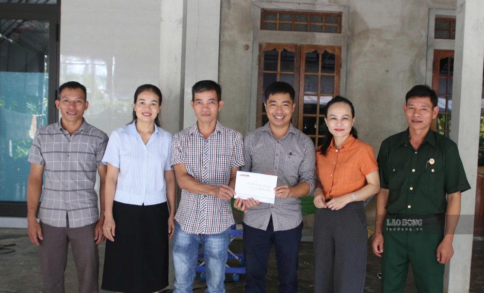 Representatives of the Golden Heart Fund of Labor (3rd from right) and Ms. Le Nguyen Huyen Trang (2nd from right) - Deputy Director of the Department of Home Affairs of Quang Tri province present gratitude gifts to representatives of the family of sick soldier Pham Xuan Hung (4th from right). Photo: Han Nguyen