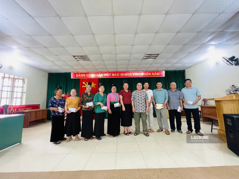 Trưởng bản Cọ, phường Chiềng An, tỉnh Sơn La (áo đỏ, đứng giữa) trao quà tới tay gia đình người có công dịp 27.7. Ảnh: Lò Hà