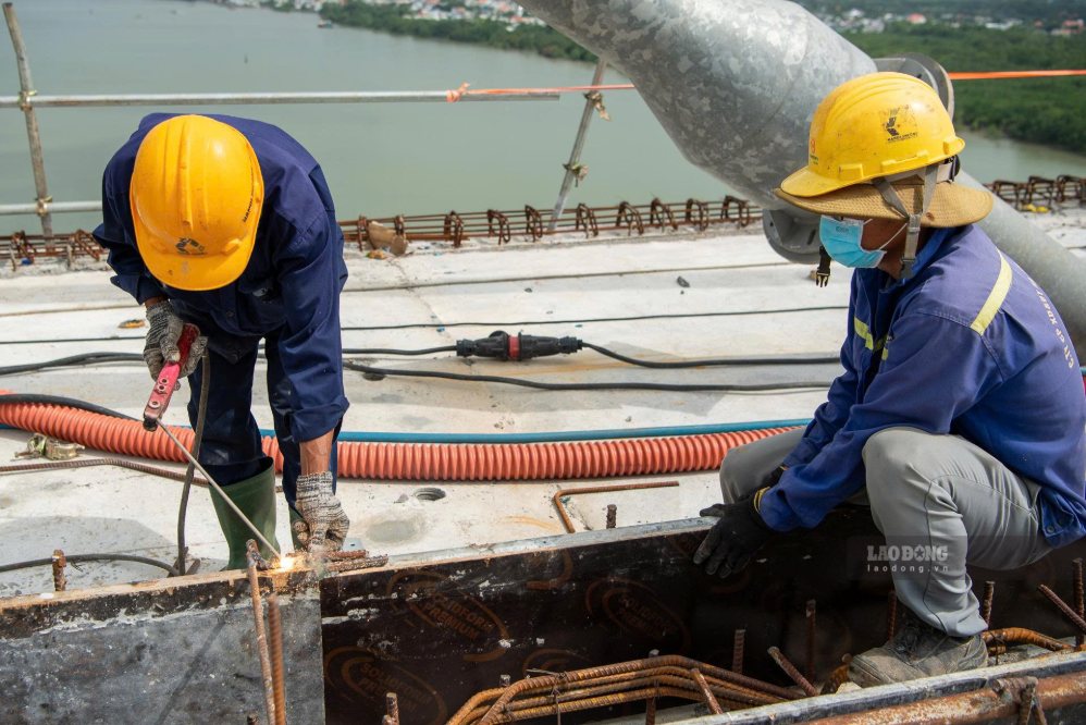 Theo ghi nhận của PV, trên mặt cầu, các nhóm thi công được bố trí dàn trải để tiếp tục hoàn thiện những hạng mục cuối cùng. Công nhân khẩn trương xử lý các vị trí thuộc đốt hợp long, kiểm tra cao độ, bảo dưỡng bê tông, lắp đặt các hạng mục phụ trợ và hoàn thiện bản mặt cầu.