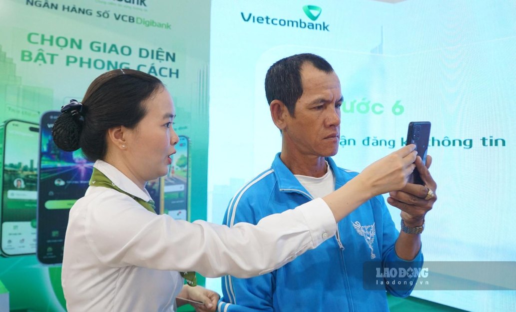 Nhân viên ngân hàng hướng dẫn người dân Cà Mau sử dụng thanh toán không dùng tiền mặt. Ảnh: Nhật Hồ.