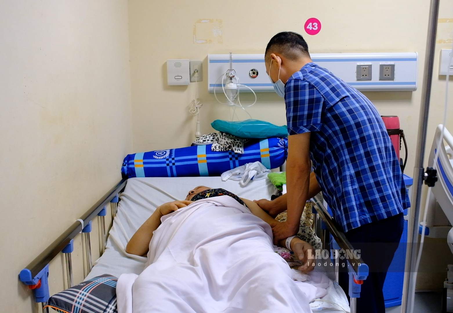 Anh Trần Phương, con trai bệnh nhân, chăm sóc mẹ đang điều trị biến chứng suy thận do tiểu đường. Ảnh: Mỷ Ly