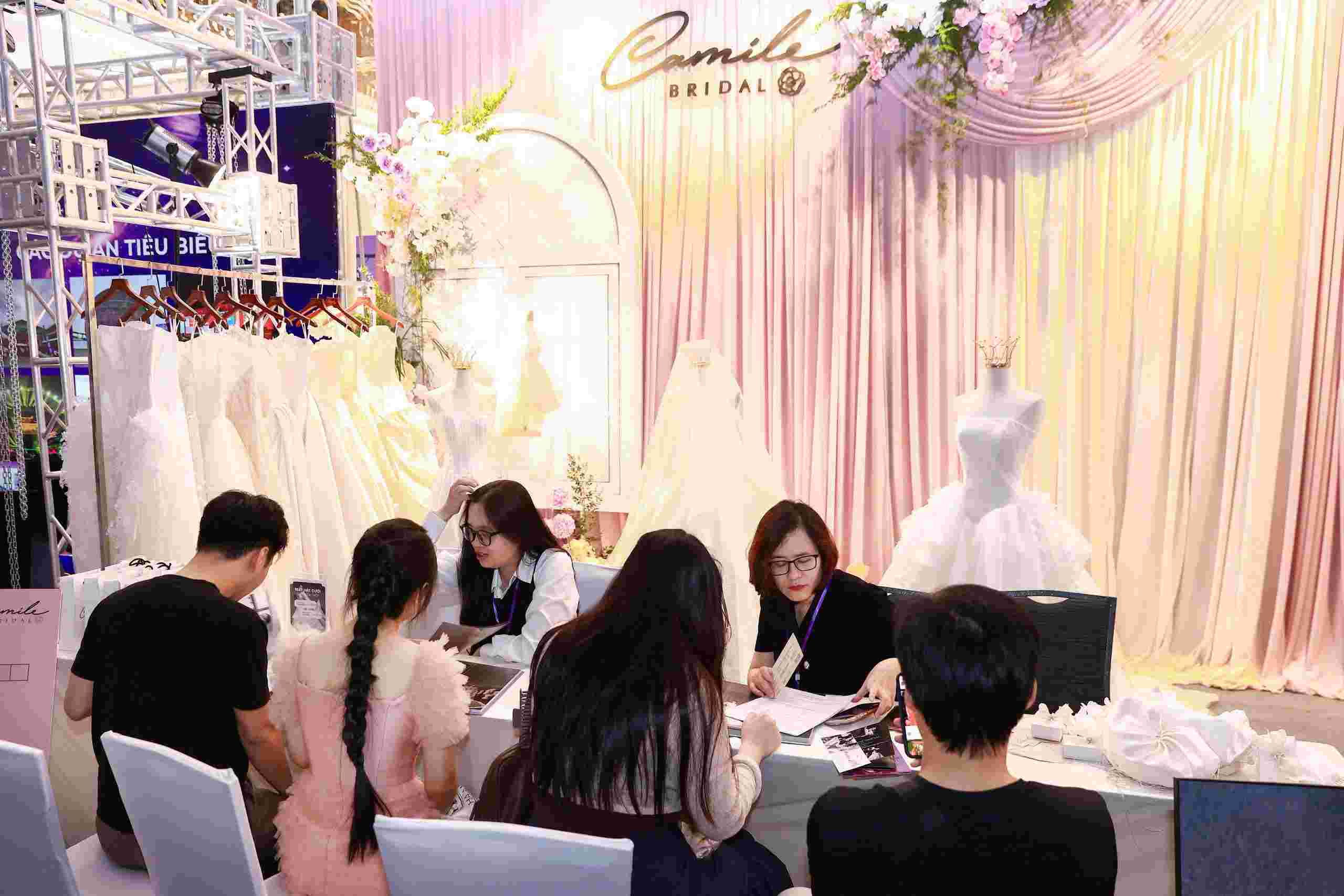 Couples together choose and refer to new wedding dress and vest designs at the wedding exhibition. Photo: Organizing Committee