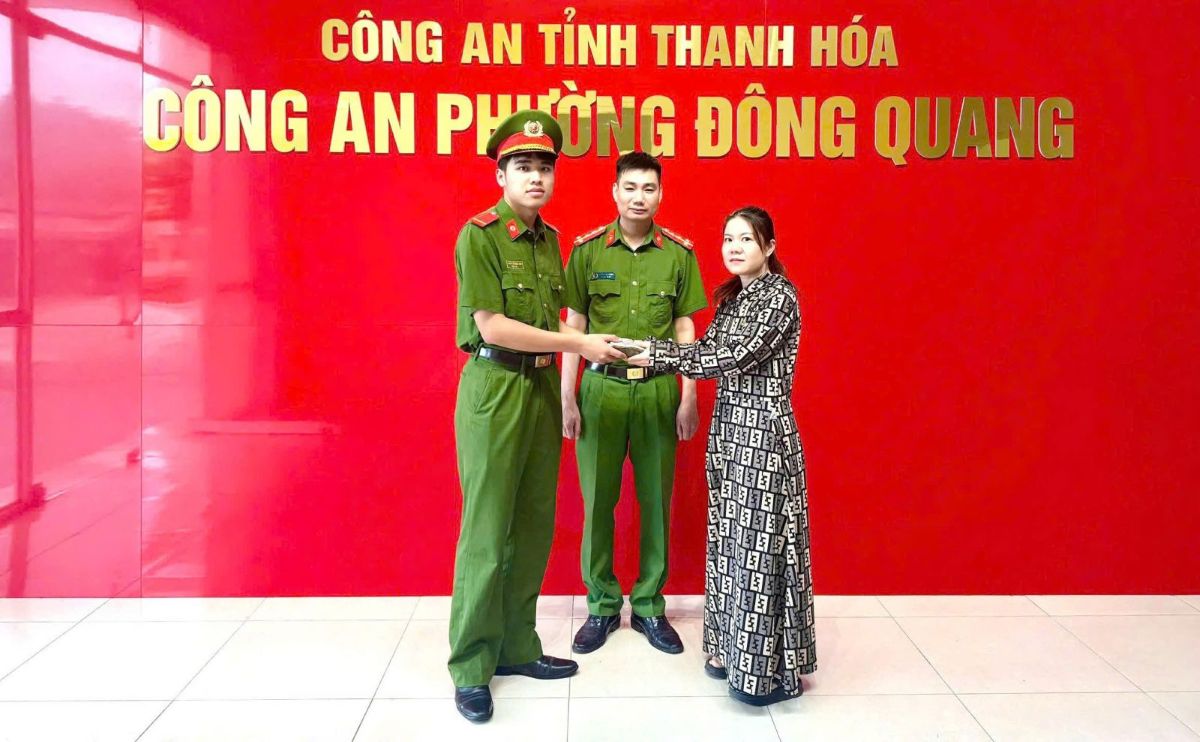 Picking up a handbag, a police officer searches for the person who dropped it to return it. Photo: Thanh Hoa Police