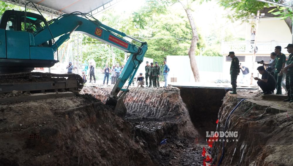 Lực lượng chức năng sử dụng máy xúc để bóc tách lớp đất mặt, mở rộng khu vực tìm kiếm xuống độ sâu hơn 2m.