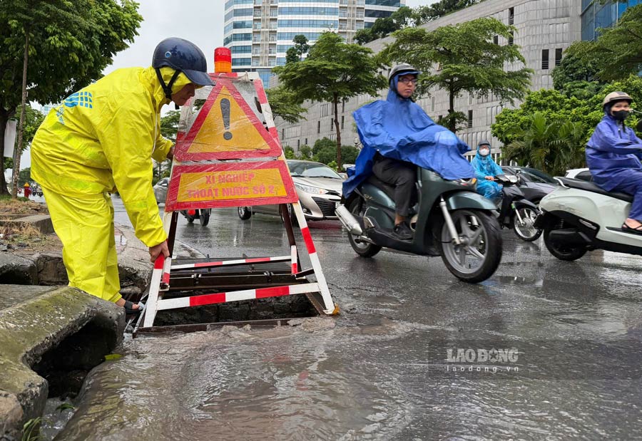 Một nhân viên Xí nghiệp thoát nước số 2 (Công ty thoát nước Hà Nội) cho biết ngay khi trời mưa lớn đã được điều động đặt biển cảnh báo tại các cống thoát nước. Ảnh: Linh Anh
