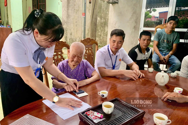 Cán bộ xã đến nhà bà Phạm Thị Nức hể hoàn thiện hồ sơ giao dịch với ngân hàng cho các cháu. Ảnh: Khánh Nga
