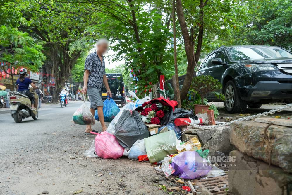 Người dân mang 2 túi rác tập kết trên đường Nguyên Hồng (Hà Nội). Ảnh: Sóng Hữu 