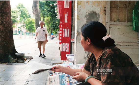 Cô Nguyễn Thị Phương Oanh sẵn sàng đưa tờ báo giấy khi thấy dáng vẻ quen thuộc của những vị khách “ruột”. Ảnh: THANH BÌNH