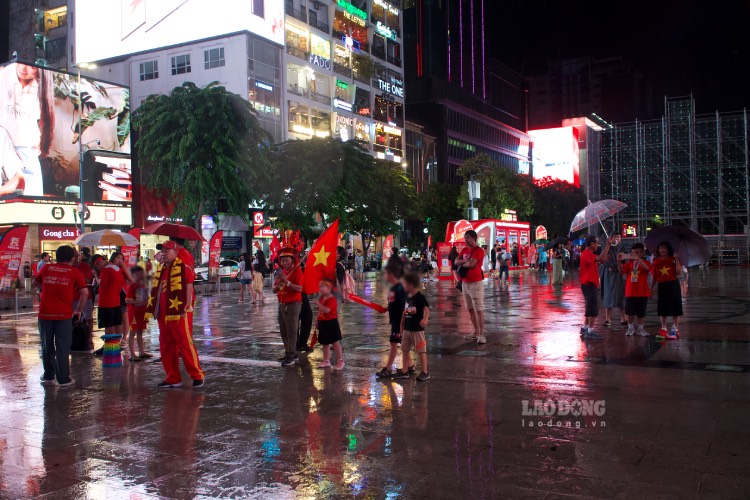 Dù trời mưa từ khoảng 18h30, người dân vẫn đổ về phố đi bộ Nguyễn Huệ, chờ theo dõi trận bán kết Việt Nam - Malaysia qua màn hình LED. Ảnh: Thái Bảo.