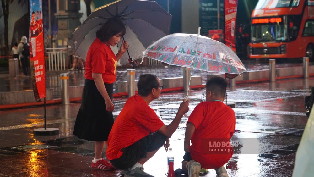 Nhiều gia đình, nhóm bạn trẻ mang theo áo mưa, thức ăn, nước uống và bạt ngồi để chuẩn bị theo dõi trận đấu. Ảnh: Thái Bảo.