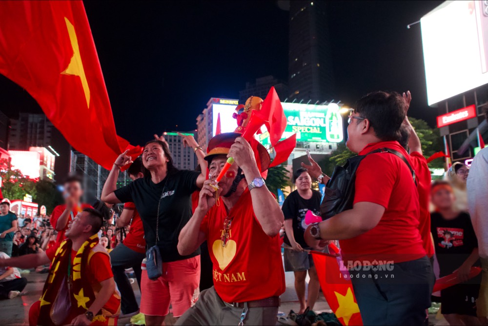 Fans raise the national flag, joining the cheering atmosphere at Nguyen Hue pedestrian street with Vietnam's goal against Malaysia. Photo: Thai Bao
