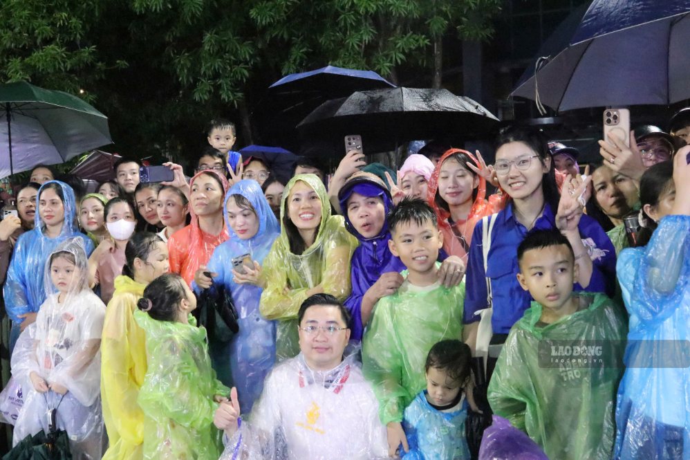 Đông đảo người dân đội mưa đứng hai bên đường theo dõi các tiết mục Carnival. Ảnh: Duy Chương