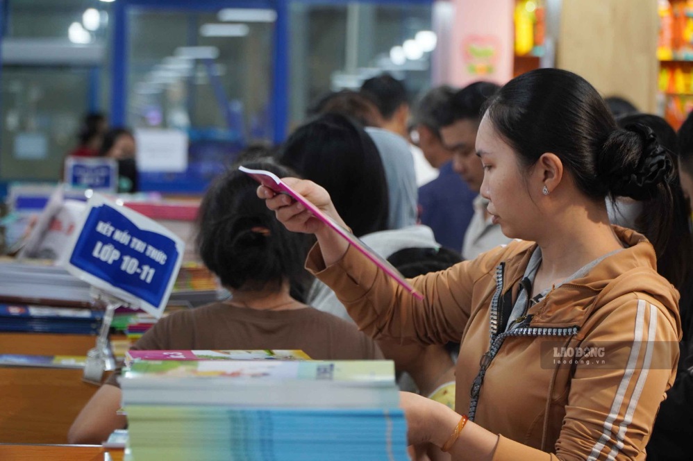 Một phụ huynh tranh thủ mua sách giáo khoa cho hai con trong sáng 19.8. Ảnh: Ngọc Ánh