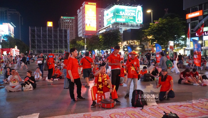 Cổ động viên mang cờ đỏ sao vàng tập trung tại phố đi bộ Nguyễn Huệ trước giờ tuyển Việt Nam thi đấu. Ảnh: Thái Bảo. 