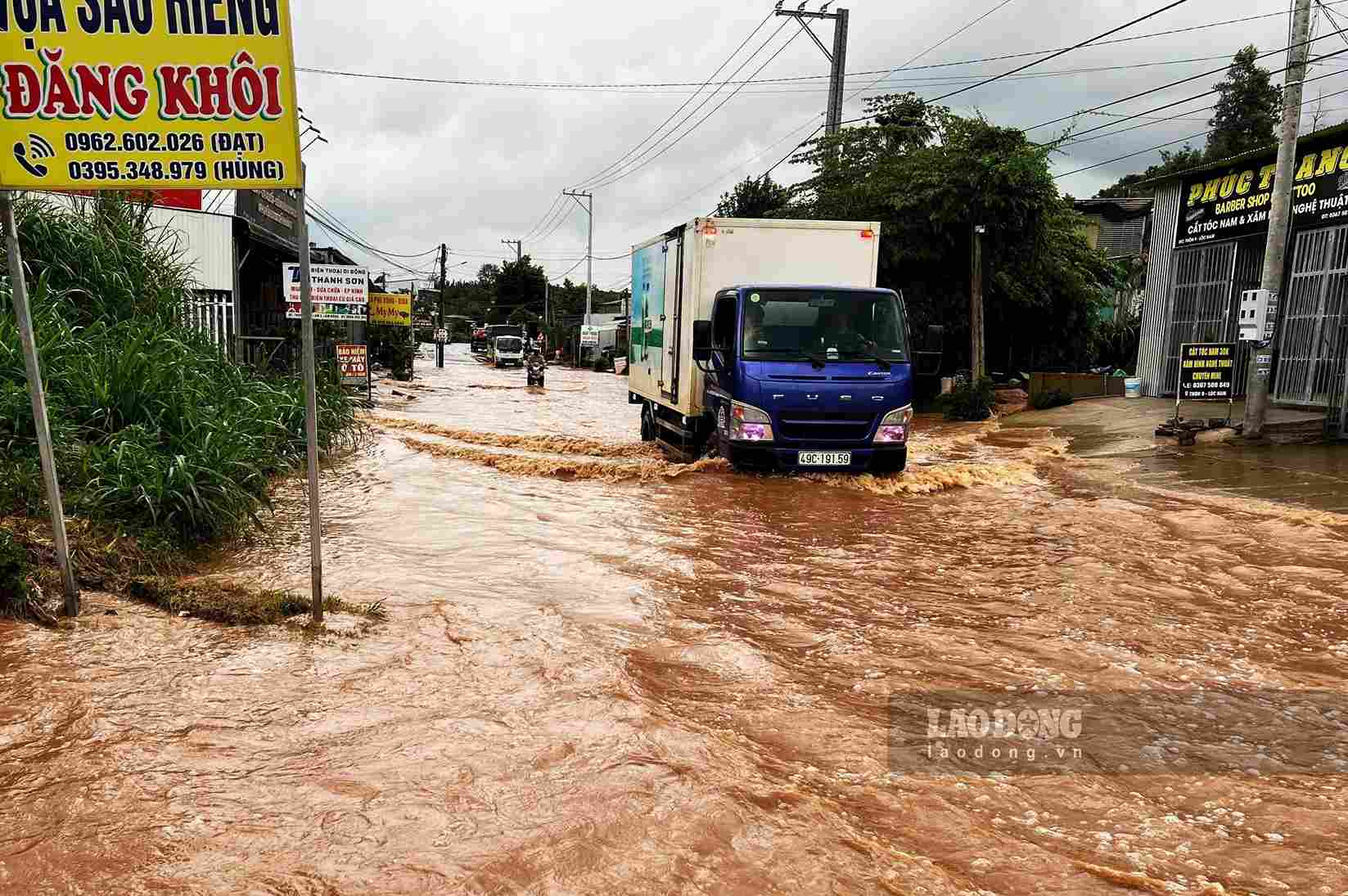 Xe tải hạng nặng lưu thông qua khu vực ngập sâu tạo thành sóng lớn khiến nước tràn vào nhà dân ven đường. Ảnh: Phúc Khánh