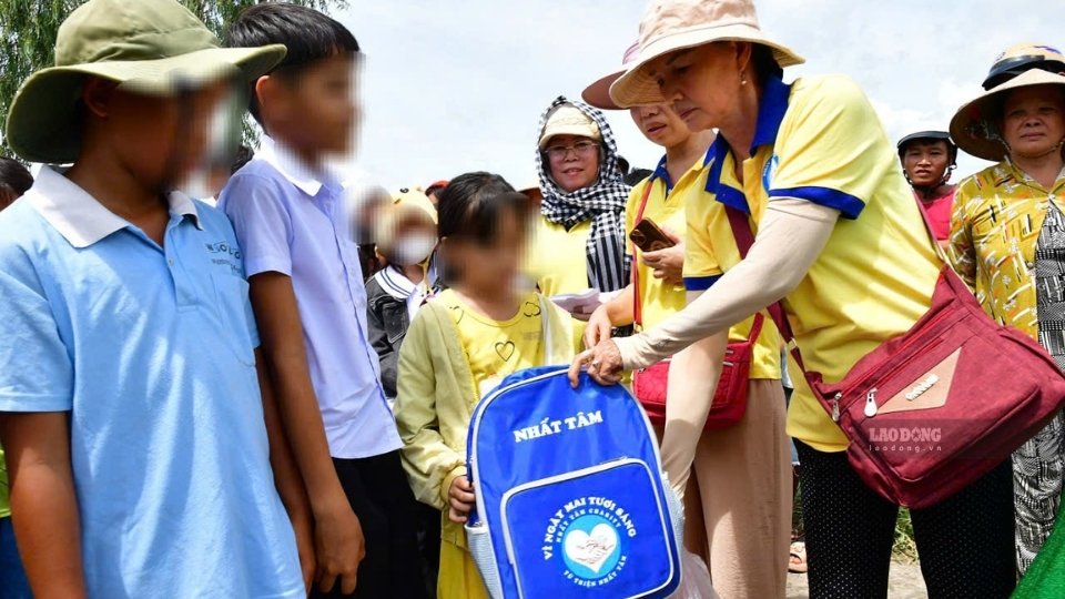 Các mạnh thường quân trao quà cho người dân và học sinh có hoàn cảnh khó khăn tại lễ khánh thành cầu Nhất Tâm 52 ở xã Hưng Mỹ. Ảnh: Hoàng Lộc