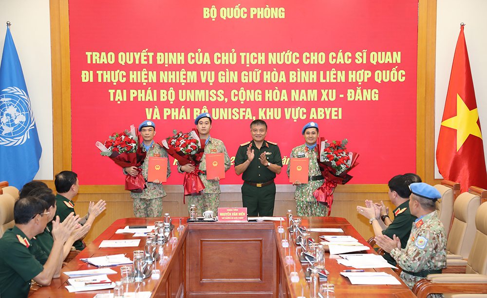 Thượng tướng Nguyễn Văn Hiền - Ủy viên Trung ương Đảng, Thứ trưởng Bộ Quốc phòng trao quyết định của Chủ tịch nước và tặng hoa chúc mừng 3 sĩ quan. Ảnh: Bộ Quốc phòng