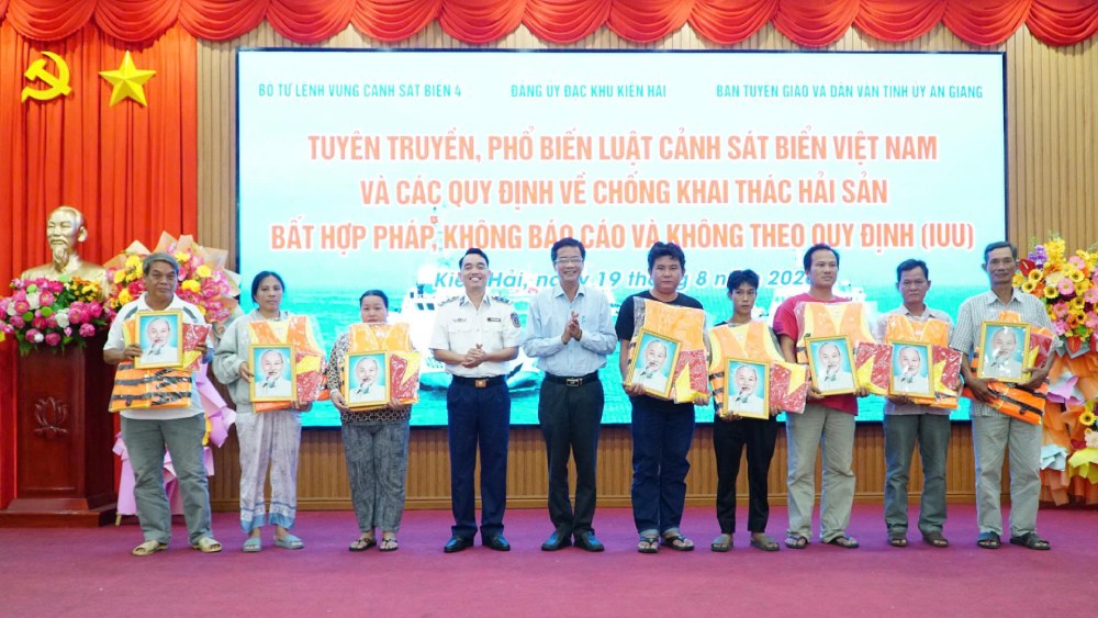 Đại diện BTL Vùng Cảnh sát biển 4 và lãnh đạo đặc khu Kiên Hải trao tặng cờ Tổ quốc, ảnh Bác Hồ và áo phao cho chủ tàu, thuyền trưởng tàu cá. Ảnh: BTL Vùng CSB4