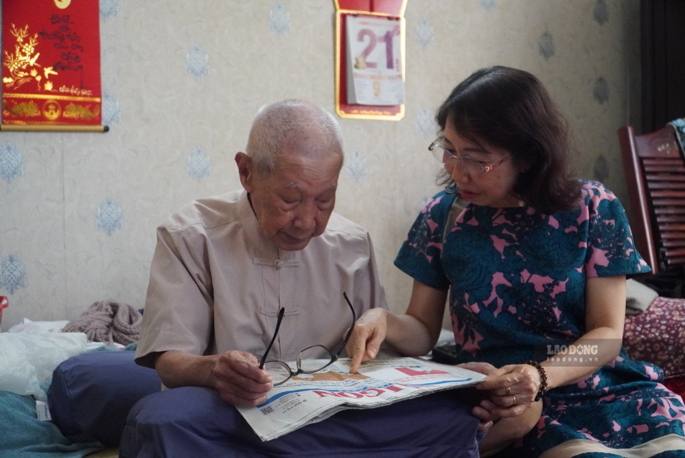 Ông Sâm đọc những dòng chữ in trên báo cho cô gái cả nghe. Ảnh: Minh Tâm