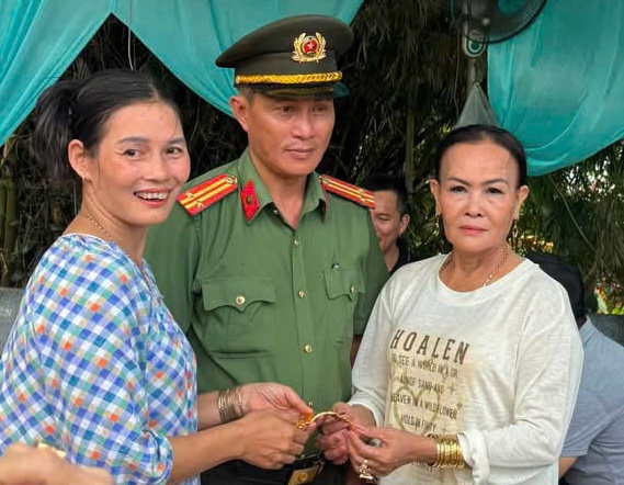 Ms. Nguyen Thi Thu Van (white shirt) receives back her gold bracelet from the police force after dropping it at the Hue Nam Palace festival. Photo: Police provided.