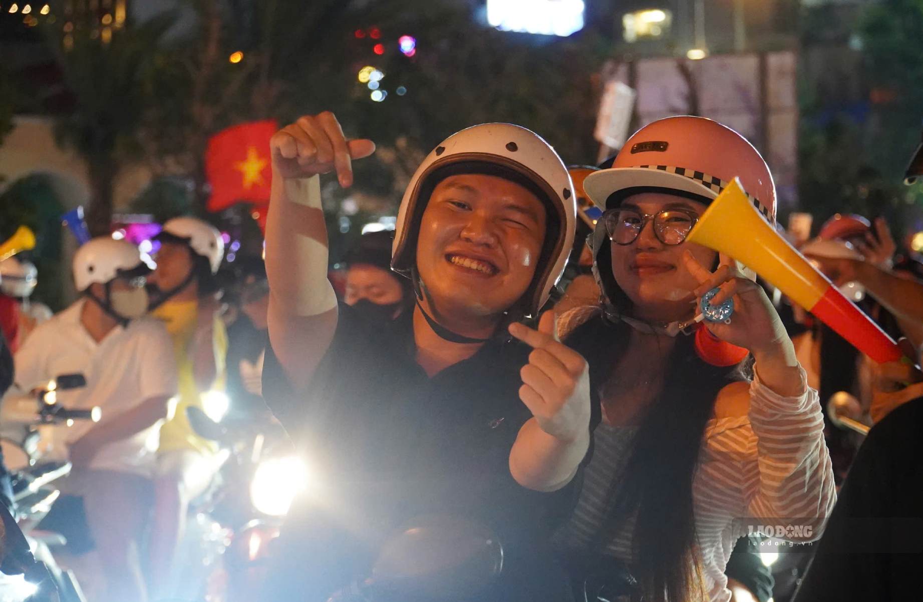 Người hâm mộ mang theo cờ, băng rôn, kèn và cup hòa vào dòng người “đi bão” sau chiến thắng của đội tuyển Việt Nam trên sân Rajamangala.