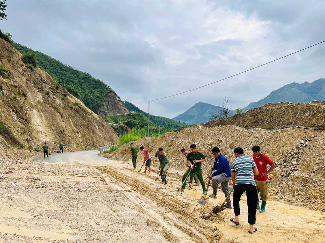 Cán bộ, chiến sĩ Công an xã Phình Hồ cùng người dân dọn bùn đất trên tuyến đường. Ảnh: Công an tỉnh Lào Cai
