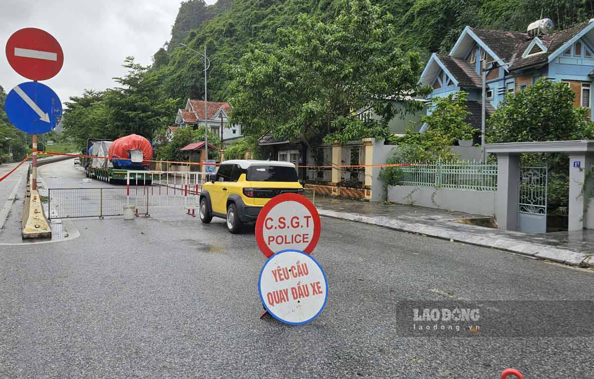 Functional forces install barriers and signs prohibiting vehicles from passing through the flooded area at Deo But slope. Photo: Doan Hung