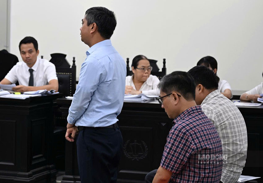 Cựu Hiệu trưởng Phạm Văn Long (áo xanh, đứng) tại phiên tòa. Ảnh: Quang Việt