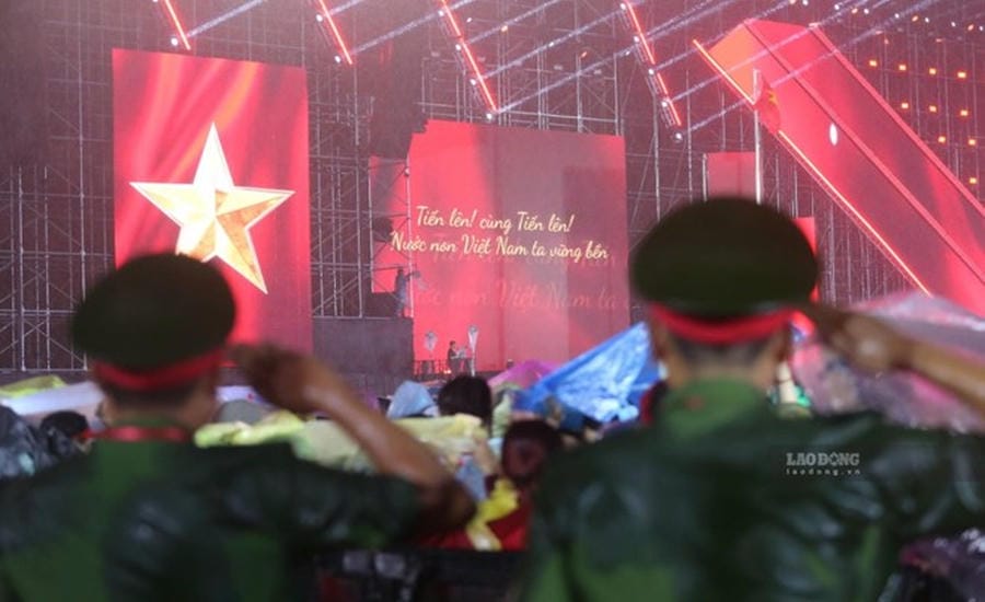70.000 espectadores bajo la fuerte lluvia cantan el Himno Nacional en el concierto "Patria en el corazón". Foto: Anh Tú