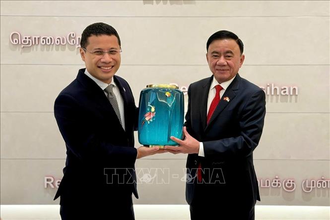 Politburo Member, Standing Secretary of the Secretariat Tran Cam Tu and Chairman of the People's Action Party of Singapore Desmond Lee present gifts. Photo: VNA