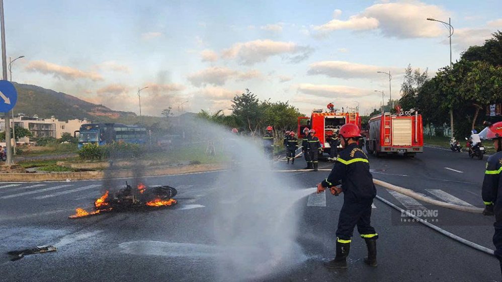 Functional forces control the fire from a motorbike that caught fire after being trapped under a truck. Photo: Phuong Linh