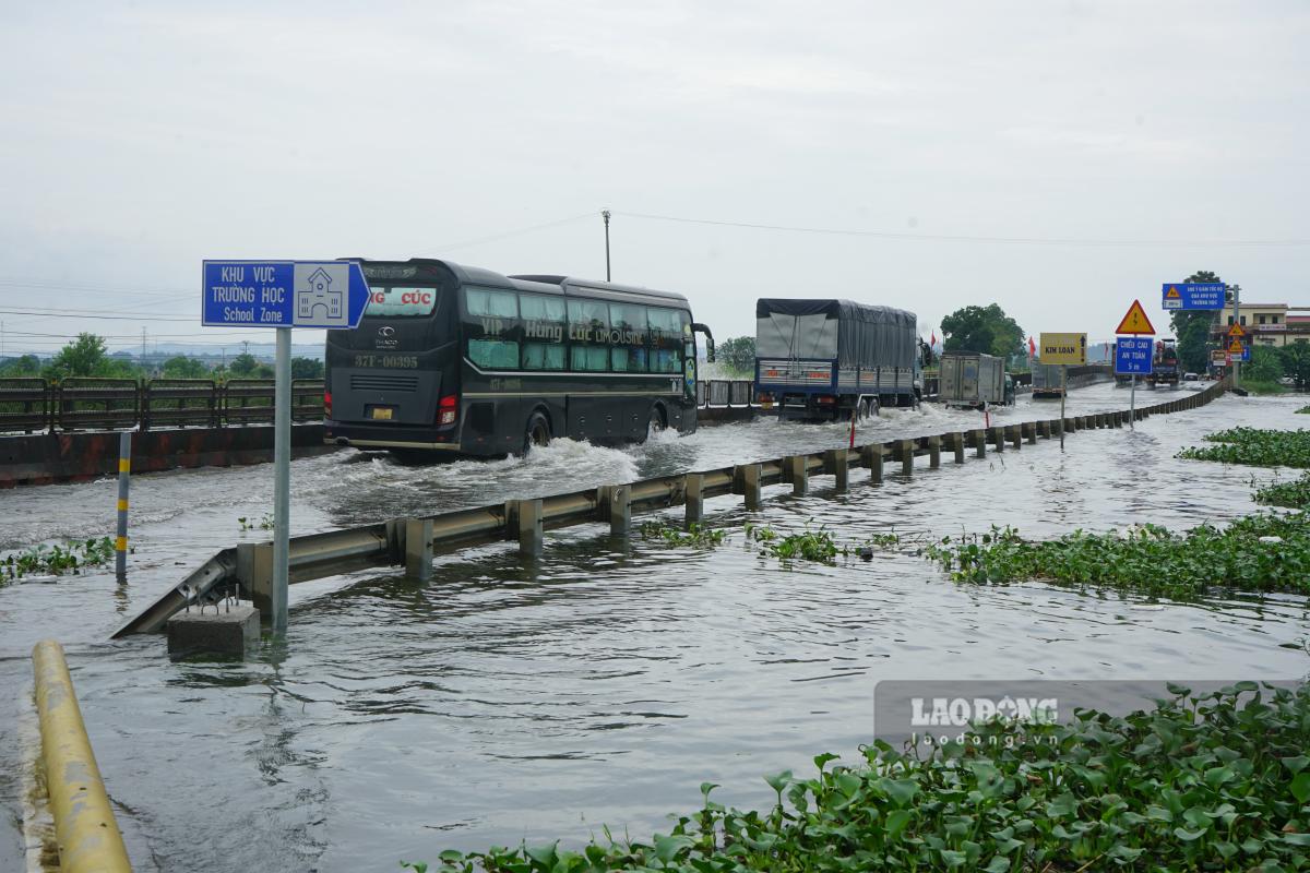 Nhiều phương tiện cỡ lớn vẫn có thể lưu thông qua điểm ngập. Ảnh: Quách Du