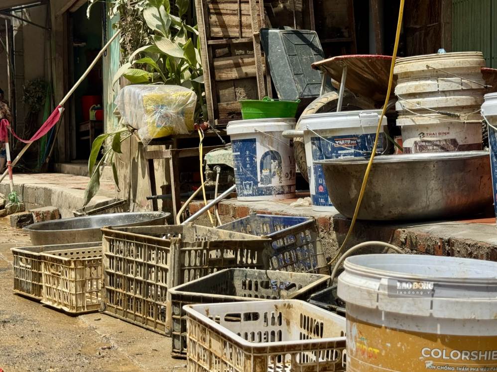 Thùng, chậu, sọt nhựa cùng nhiều dụng cụ phục vụ sinh hoạt, kinh doanh được tập kết trước cửa nhà để cọ rửa. Không ít tài sản bị ngâm trong nước nhiều ngày, phủ kín bùn và có nguy cơ không thể tiếp tục sử dụng. Ảnh: Khánh Linh